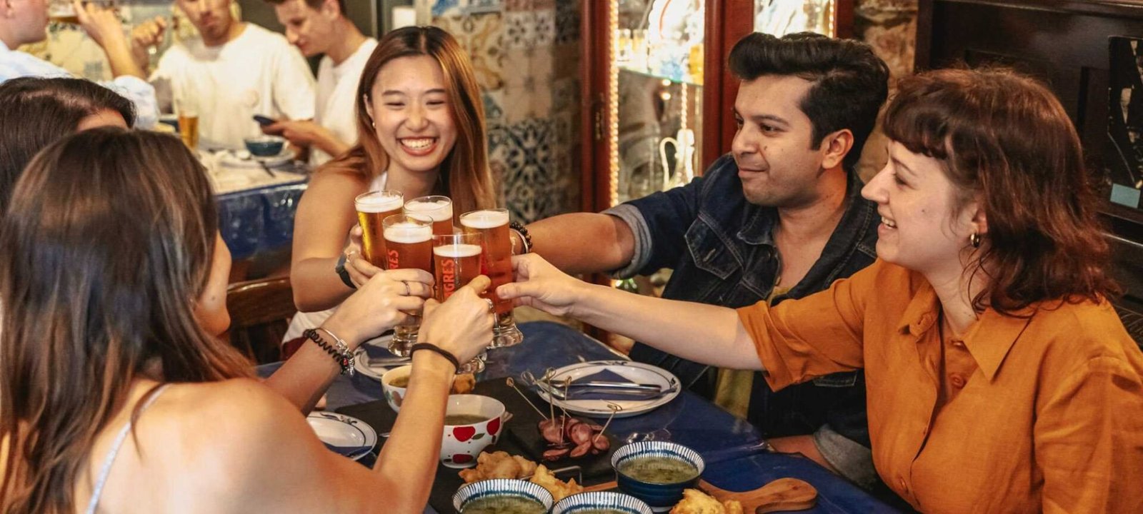 Small group clinking beer glasses on a Lisbon Food Tour