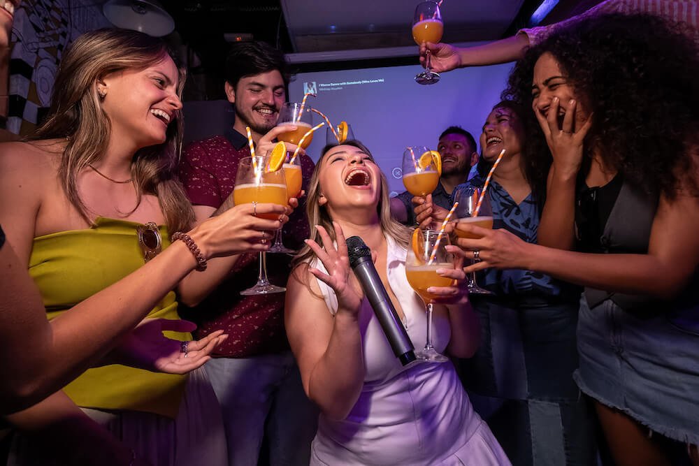 Girl singing karaoke in Rome surrouned by friends