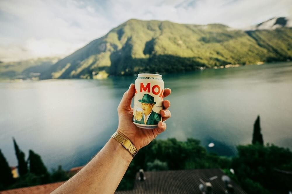 Birra Moretti, one of the top Italian beers, being held up against a mountain background